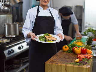 Image showing Chef holding dish of fried Salmon fish fillet