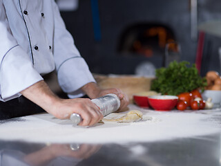 Image showing chef preparing dough for pizza with rolling pin