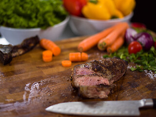 Image showing Juicy slices of grilled steak on wooden board