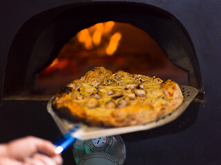 Image showing chef removing hot pizza from stove