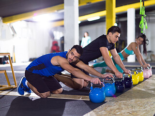 Image showing young athletes doing pushups with kettlebells