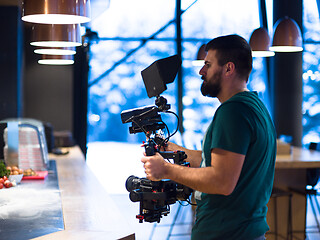 Image showing videographer recording while team cooks and chefs preparing meal