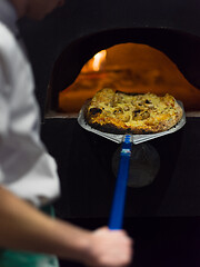 Image showing chef removing hot pizza from stove