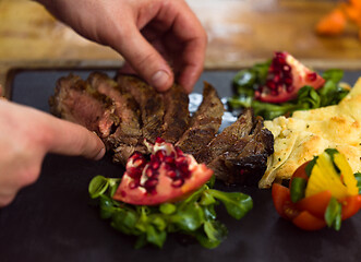 Image showing closeup of Chef hands serving beef steak