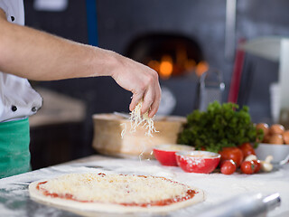 Image showing chef sprinkling cheese over fresh pizza dough