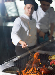 Image showing chef cooking steak with vegetables on a barbecue