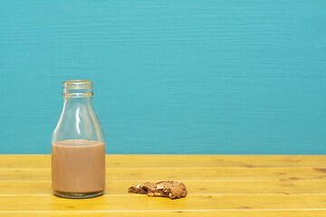 Image showing Bottle half full with chocolate milkshake with a half-eaten cook