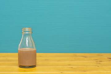 Image showing Glass milk bottle half full with chocolate milkshake