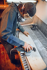 Image showing Carpenter using circular saw for cutting wooden boards.