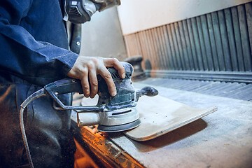 Image showing Carpenter using circular saw for cutting wooden boards.