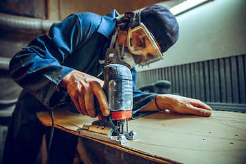 Image showing Carpenter using circular saw for cutting wooden boards.