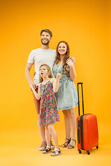 Image showing Happy parent with daughter and suitcase at studio isolated on yellow background