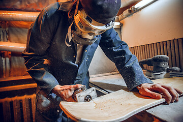 Image showing Carpenter using circular saw for cutting wooden boards.