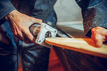 Image showing Carpenter using circular saw for cutting wooden boards.