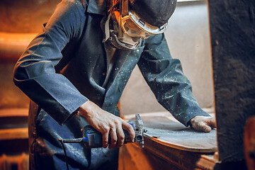 Image showing Carpenter using circular saw for cutting wooden boards.