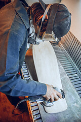 Image showing Carpenter using circular saw for cutting wooden boards.