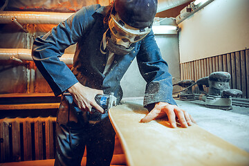 Image showing Carpenter using circular saw for cutting wooden boards.