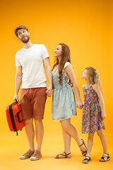 Image showing Happy parent with daughter and suitcase at studio isolated on yellow background