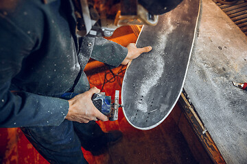 Image showing Carpenter using circular saw for cutting wooden boards.