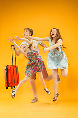 Image showing Happy parents with daughter and suitcase at studio isolated on yellow background