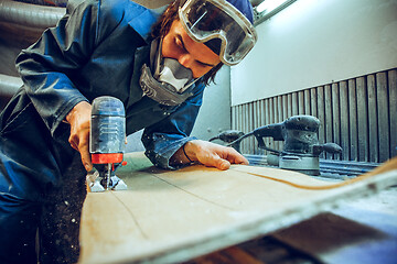 Image showing Carpenter using circular saw for cutting wooden boards.