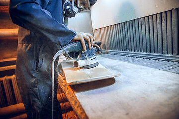 Image showing Carpenter using circular saw for cutting wooden boards.