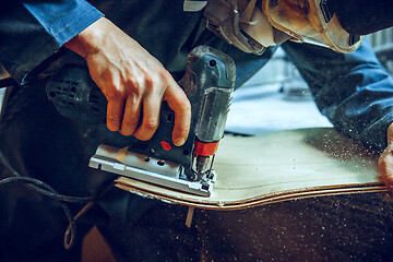 Image showing Carpenter using circular saw for cutting wooden boards.