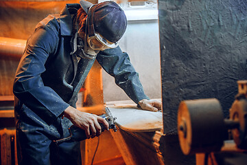 Image showing Carpenter using circular saw for cutting wooden boards.