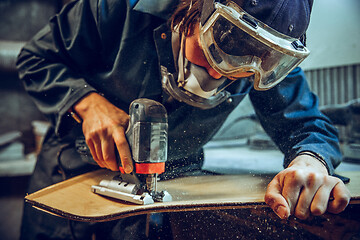 Image showing Carpenter using circular saw for cutting wooden boards.