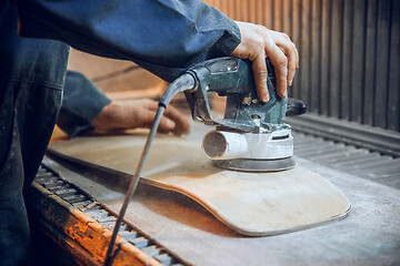 Image showing Carpenter using circular saw for cutting wooden boards.