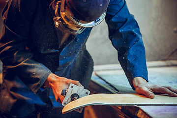 Image showing Carpenter using circular saw for cutting wooden boards.