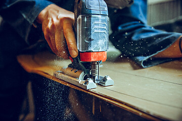 Image showing Carpenter using circular saw for cutting wooden boards.