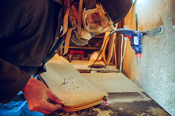 Image showing Portrait of handsome carpenter working with skate at workshop