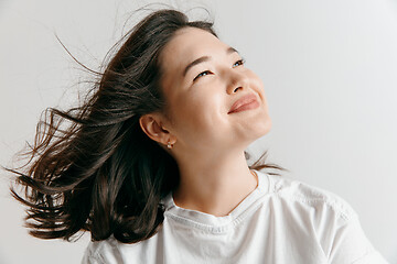 Image showing Happy asian woman standing and smiling against gray background.