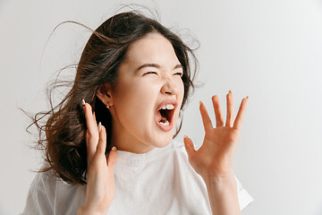 Image showing The young emotional angry woman screaming on gray studio background