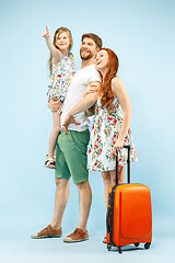 Image showing Happy parent with daughter and suitcase at studio isolated on blue background