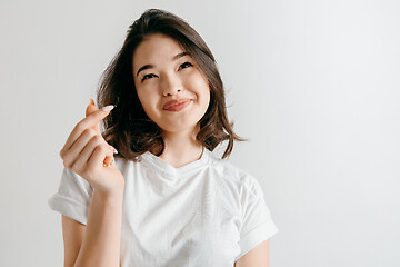 Image showing Happy asian woman standing and smiling against gray background.