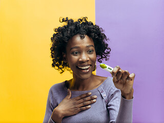 Image showing Smiling young woman looking on pregnancy test