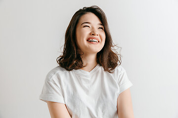 Image showing Happy asian woman standing and smiling against gray background.