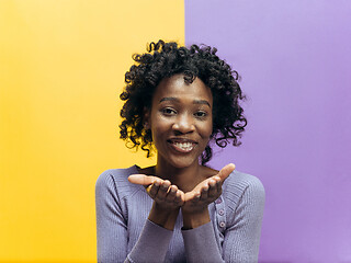Image showing The happy african woman standing and smiling against color background.
