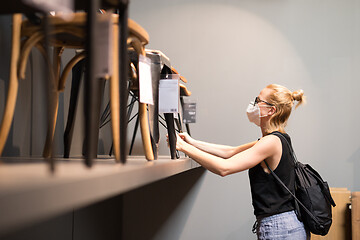 Image showing New normal during covid epidemic. Caucasian woman shopping at retail furniture and home accessories store wearing protective medical face mask to prevent spreading of corona virus