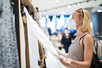 Image showing Fashionable woman wearing protective face mask shopping clothes in reopen retail shopping store. New normal lifestyle during corona virus pandemic