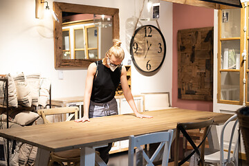 Image showing New normal during covid epidemic. Caucasian woman shopping at retail furniture and home accessories store wearing protective medical face mask to prevent spreading of corona virus