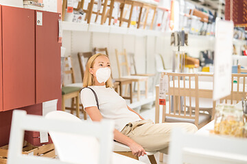 Image showing New normal during covid epidemic. Caucasian woman shopping at retail furniture and home accessories store wearing protective medical face mask to prevent spreading of corona virus