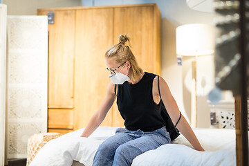 Image showing New normal during covid epidemic. Caucasian woman shopping at retail furniture and home accessories store wearing protective medical face mask to prevent spreading of corona virus