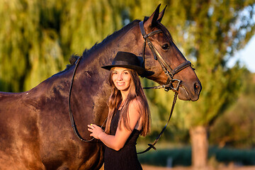 Image showing Beautiful girl hugs a horse in the rays of the setting sun