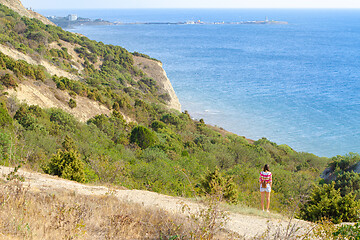 Image showing A girl stands on a hill and looks into the distance at the sea