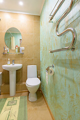 Image showing Fragment of the bathroom interior, view of the toilet and washbasin, a heated towel rail is installed on the wall