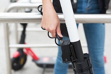 Image showing User safely parking electric scooter and locking it to a fence. Eco friendly green modern urban mobility concept of sharing transportation with electric scooters for rent in Ljubljana, Slovenia