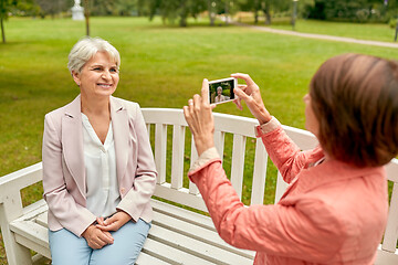 Image showing senior woman photographing her friend at park